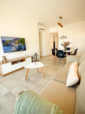 Una sala de estar moderna con una televisión de pantalla plana, una mesa de comedor y un sofá.