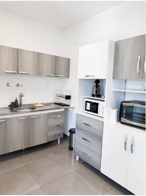 Eine moderne Küche mit grauen Schränken, einer eingebauten Mikrowelle und einem Toaster.