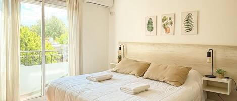 Un dormitorio con cama, lámpara colgante, ventana con cortinas y decoración en la pared.