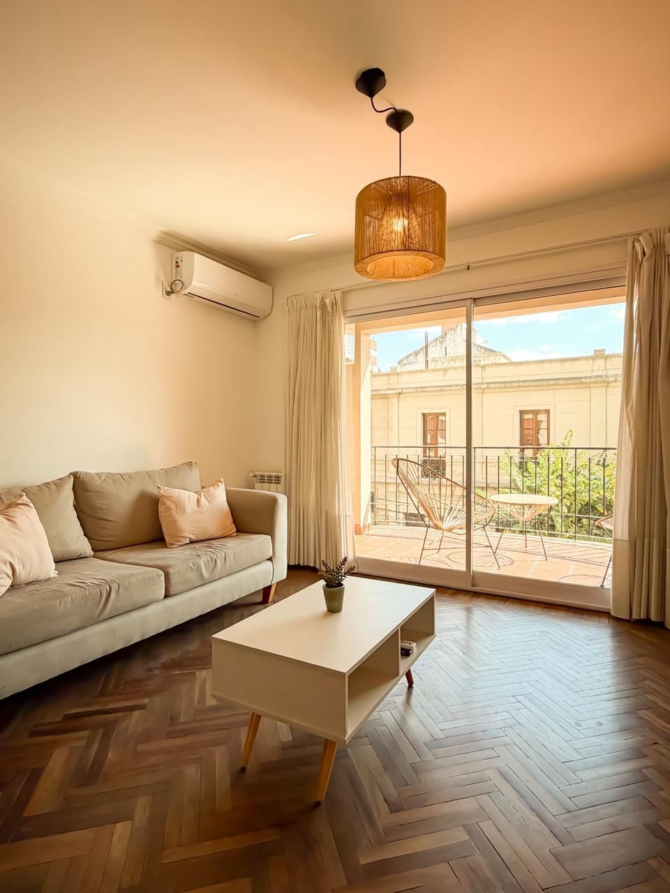 A living room with a sofa, a coffee table, and a view of a courtyard through a sliding glass door.