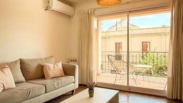 A living room with a sofa, a coffee table, and a view of a courtyard through a sliding glass door.
