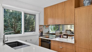 Eine moderne Küche mit großem Fenster, Holzschränken und einer Edelstahlspüle.