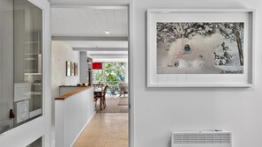 Ein Flur mit Essbereich, einem gerahmten Foto an der Wand und einem Lüftungsgitter am Boden.