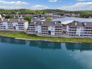 Ein Hotel am Wasserufer mit mehreren Balkonen, einem Schwimmbad und Blick auf den See und die umliegenden Gebäude.
