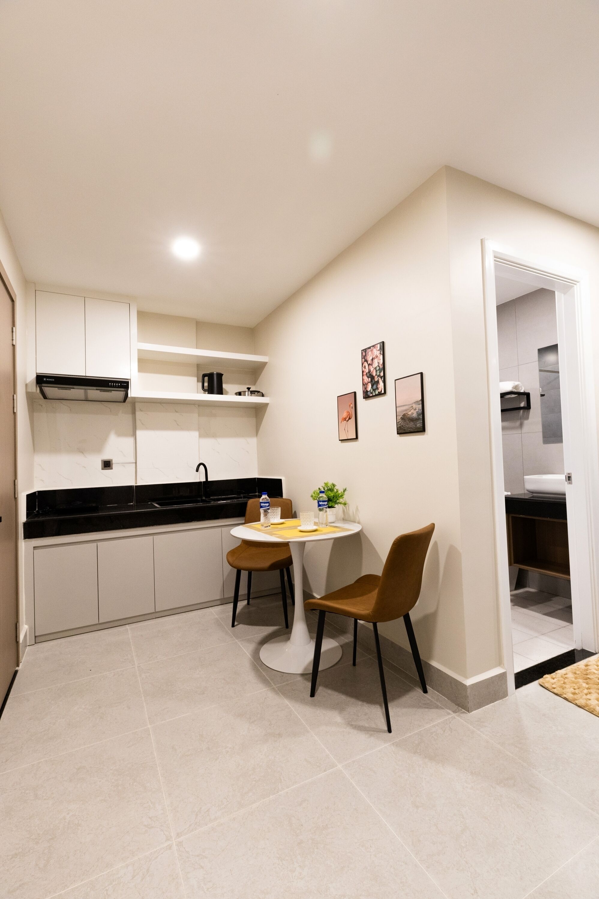 A compact kitchen with a dining area, white cabinetry, a black countertop, and a small table with chairs.