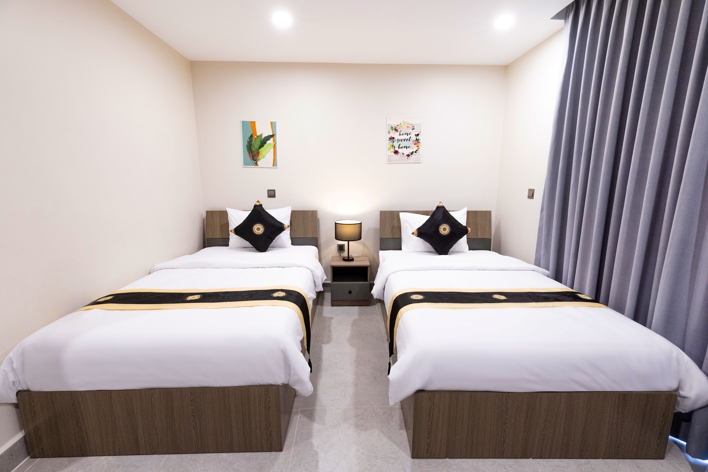 A hotel room with two beds, a nightstand with a lamp, and a wall with two decorative pieces.