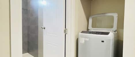 A bathroom with a shower, a toilet, and a washing machine.