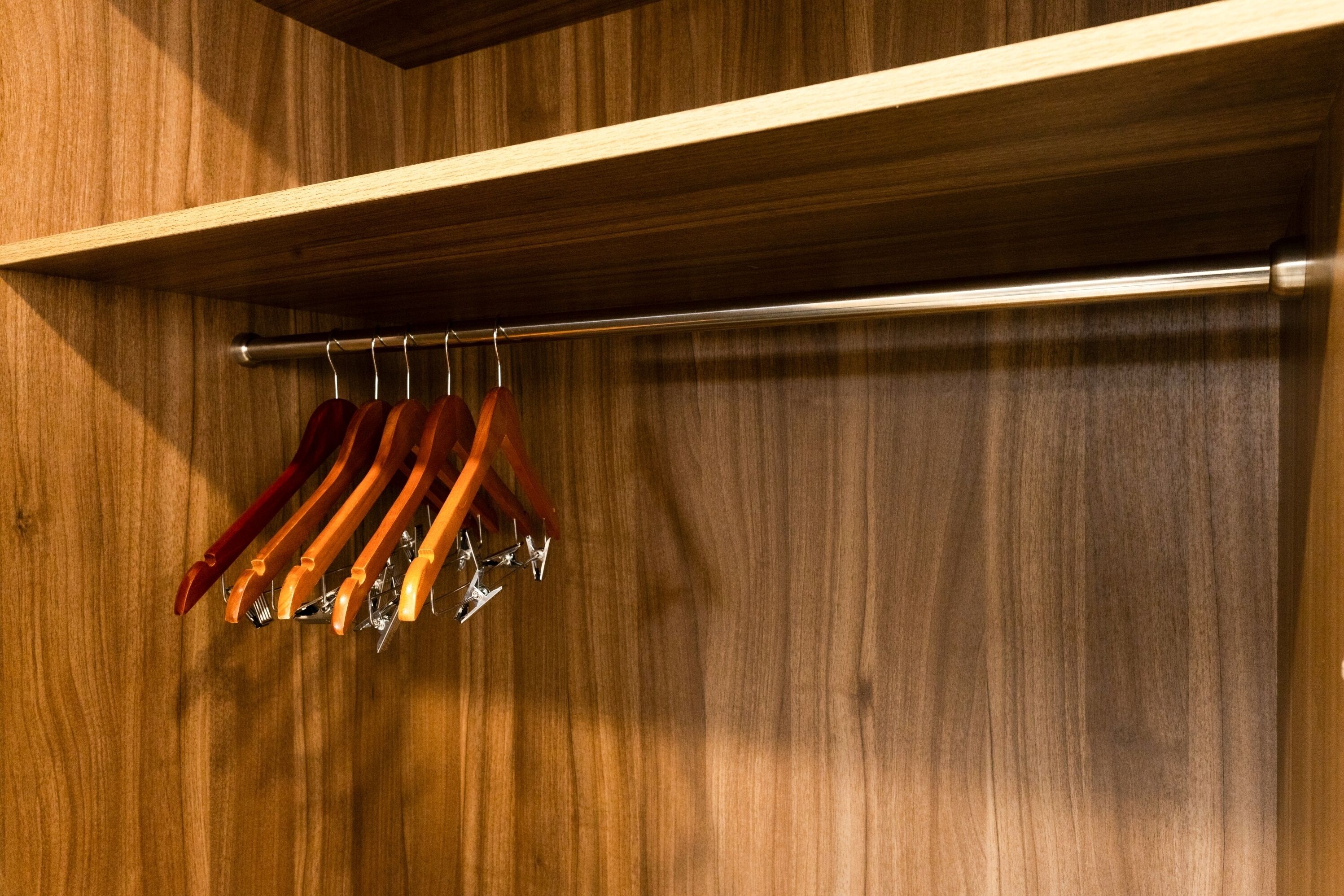A wooden wall with a metal rod rack holding several hangers.