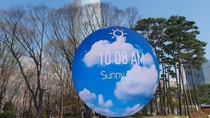 A tall building with a clear sky and a weather forecast sign indicating sunny weather.