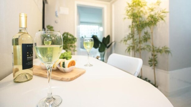 A table with a bottle of white wine, a glass of wine, and a wooden board with food.
