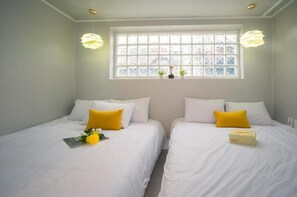 Una habitación con dos camas, ventana con vistas y lámparas colgantes.