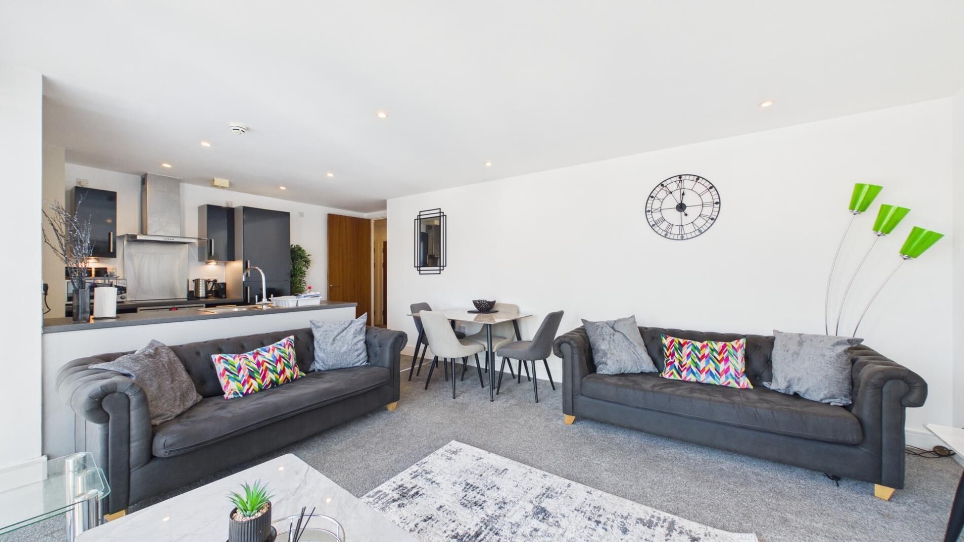 Ein modernes Wohnzimmer mit zwei Sofas, einem Esstisch und einer Küche im Hintergrund.