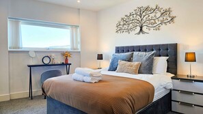 Ein Hotelzimmer mit Bett, Schreibtisch, Stuhl, Fenster und einem Wandbild.