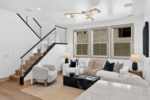 Ein modernes Wohnzimmer mit Treppe, einem weißen Sofa, einem Couchtisch und einer Lampe.