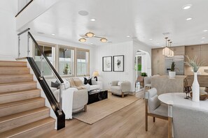 Ein modernes Wohnzimmer mit Treppe, Essbereich und Küche.