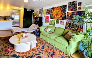 Ein Wohnzimmer mit einem grünen Sofa, einem weißen Couchtisch und einem Teppich mit floralem Muster.
