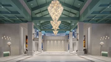 Um hall espaçoso com teto alto, um lustre central e parede estampada.