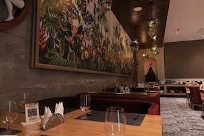 A restaurant with a large tropical mural, wooden tables, and red cushioned seating. - Pride Elite, Dwarka (Dwarka)