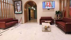 A lobby with two red sofas, a marble coffee table, a TV, and a framed artwork on the wall.