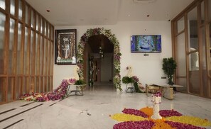 A hotel lobby with a marble floor, floral decorations, a statue, and a painting. - Pride Elite, Dwarka (Dwarka)