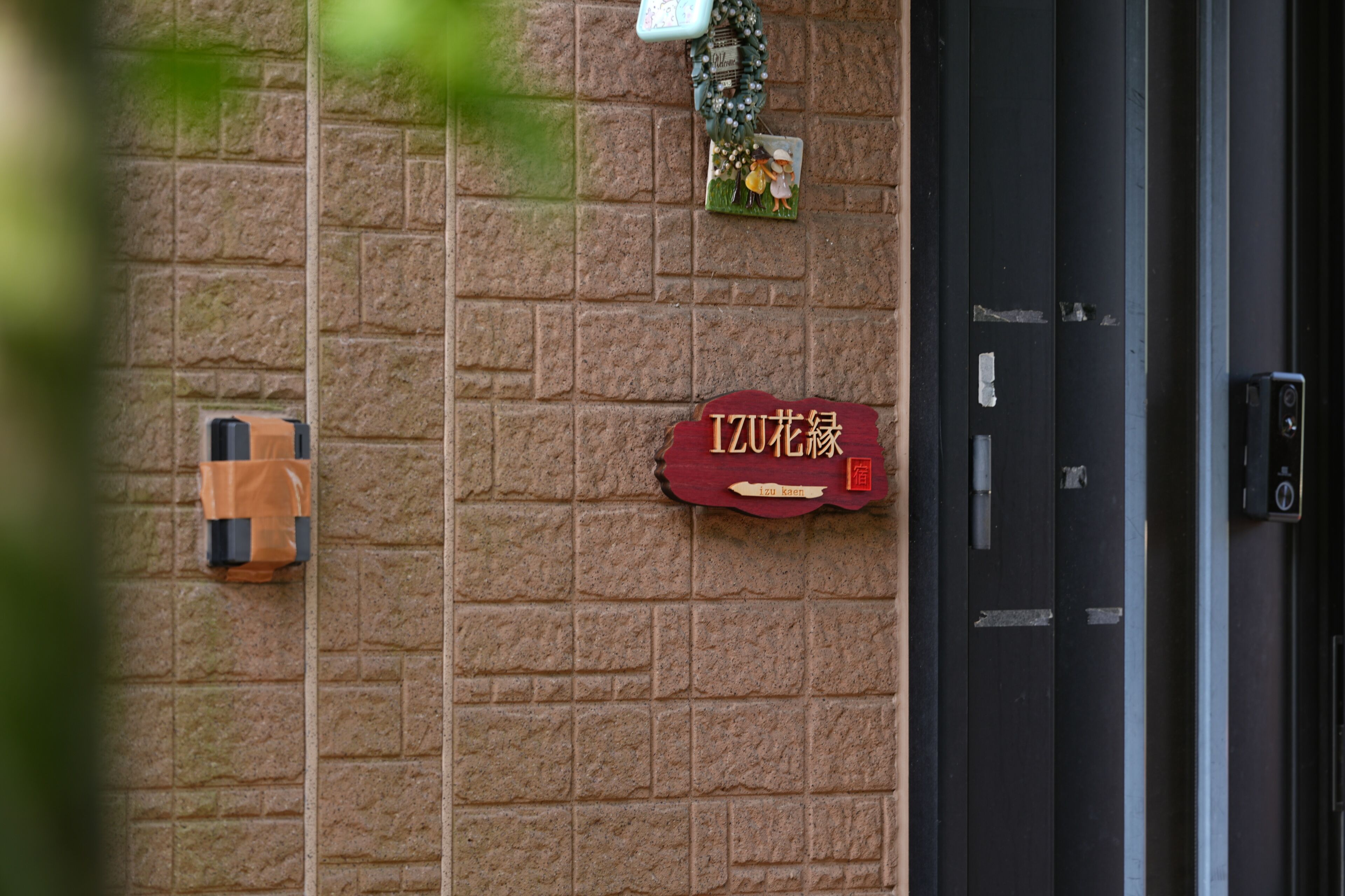 A brick wall with a door, a sign with Chinese characters, and a small decorative item above the door.