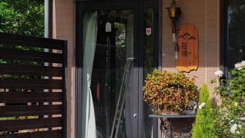 A wooden sign with characters, a glass door, a metal gate, and a potted plant with foliage.