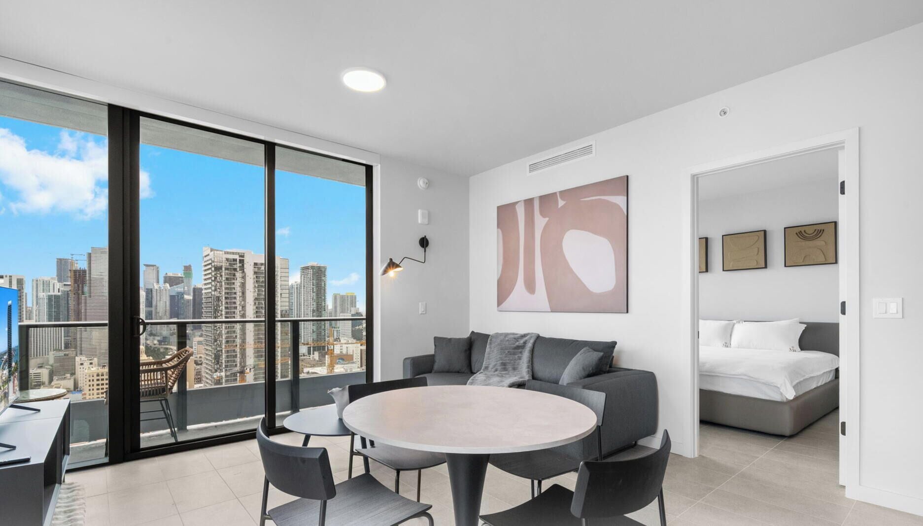 Un appartement moderne doté d’un balcon, d’une table de salle à manger ronde, d’un canapé et d’un lit.