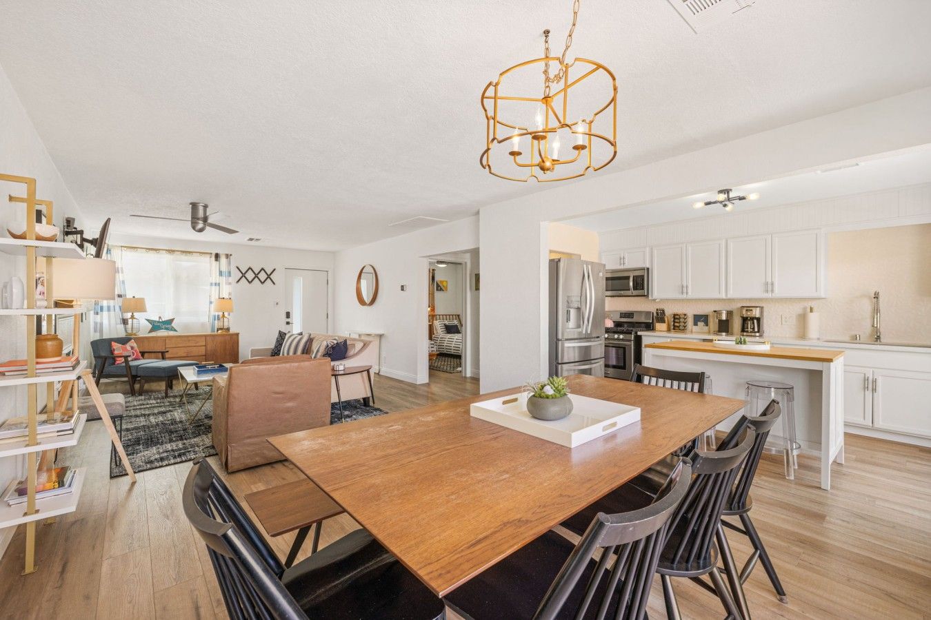 A spacious living area with a dining table, sofas, and a kitchen in the background.
