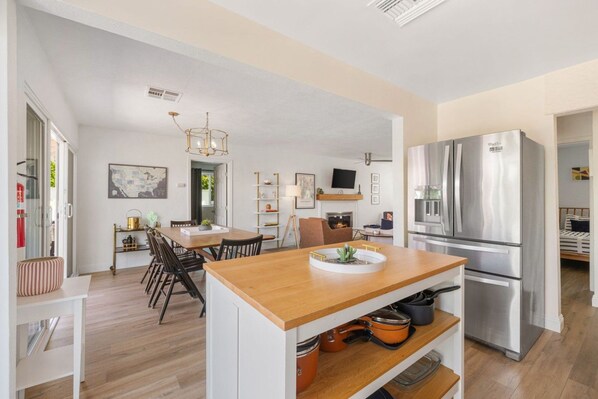 A modern kitchen with a wooden dining table, stainless steel appliances, and a fireplace. - Desert Divas Escape - Palm Springs (Palm Springs)