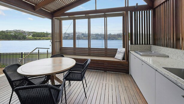 A deck with a table and chairs, a built-in bench, and a view of a lake. - Reflections Holiday Parks Evans Head (Evans Head)