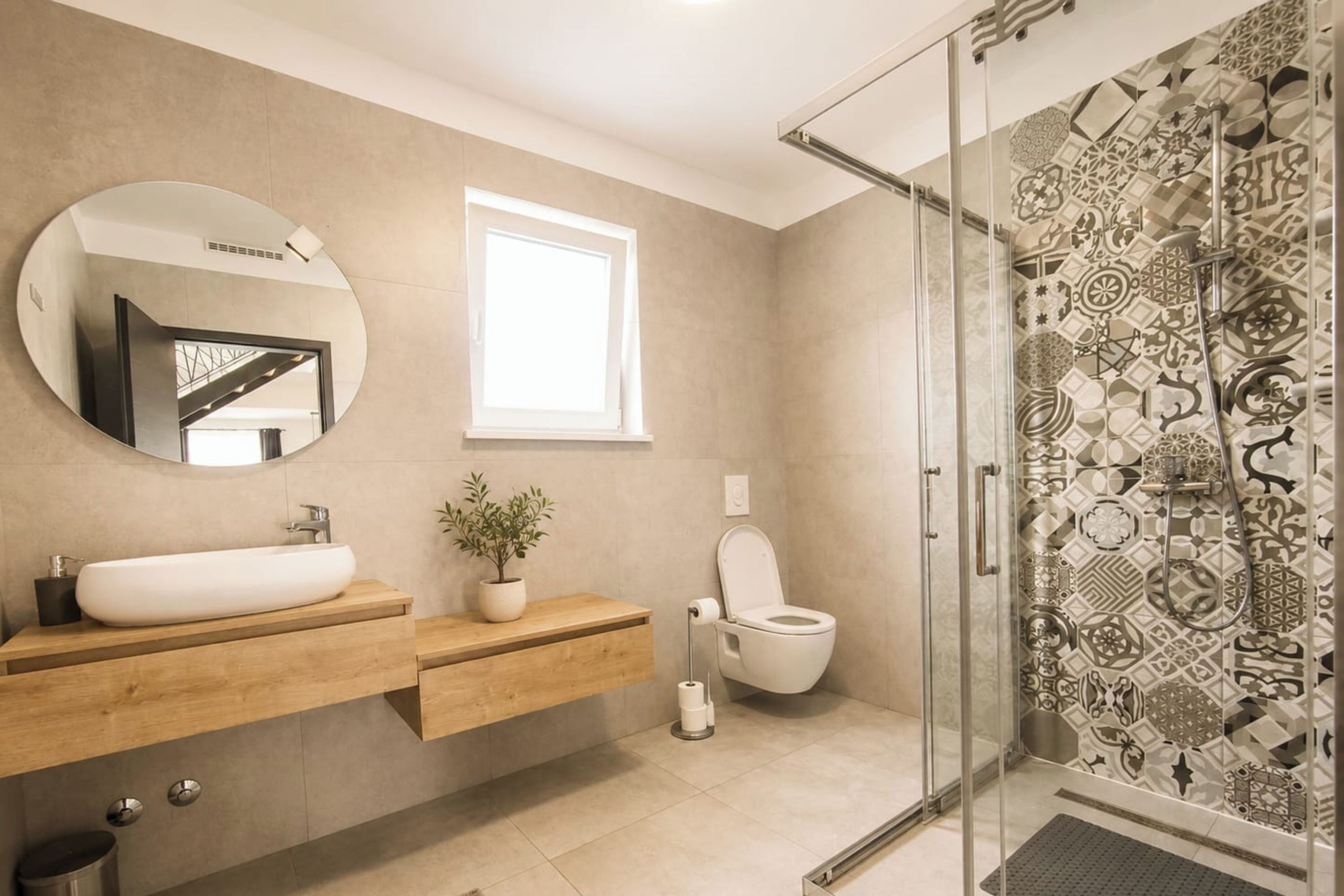 Ein modernes Badezimmer mit einem großen Spiegel, einem Waschbecken, einer Toilette und einer Dusche mit gemusterten Fliesen.