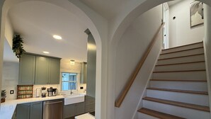 Eine Küche mit einer Holztreppe, einer Kaffeemaschine und einem Spülbecken.