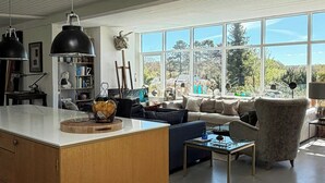 A spacious living area with a large window, a central island, and a high ceiling.