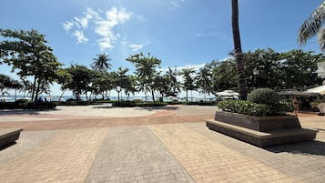 Un'area esterna pavimentata con palme e vista sul mare.