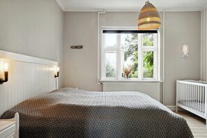 A bedroom with a bed, a window, a crib, and wall-mounted lights. - Soul in a 100-year-old villa on Langeland (Tranekær)