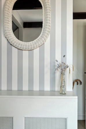 A mirror on a wall with vertical stripes, a vase with dried plants, and a white cabinet below. - Soul in a 100-year-old villa on Langeland (Tranekær)
