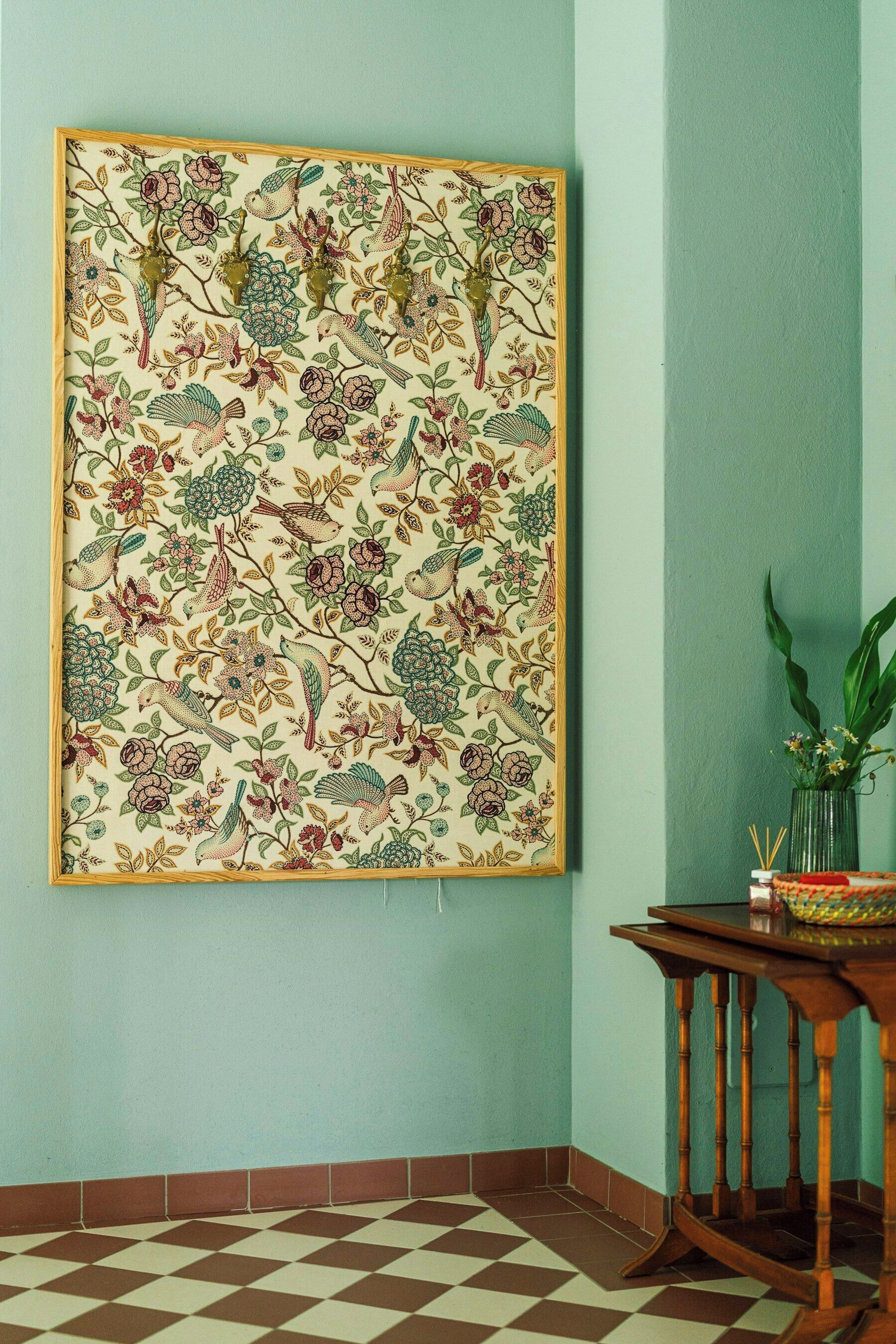 Ein Zimmer mit Schachbrettboden, einem gerahmten Blumenbild an der Wand und einem kleinen Tisch mit einer Vase.