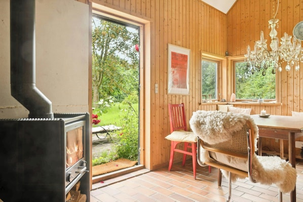 A wooden interior with a fireplace, a dining table, and a chair.