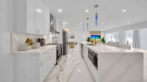 A modern kitchen with white cabinetry, a marble floor, and a central island.