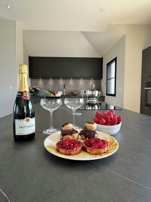 A modern kitchen with a bottle of champagne, glasses, and dessert on the counter. - Wellness villa with sea view in Brittany (Plouider)