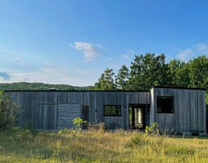 A rustic wooden building with a garage door, a small entrance, and a window. - Architect-house near Stenshuvud (Simrishamn)