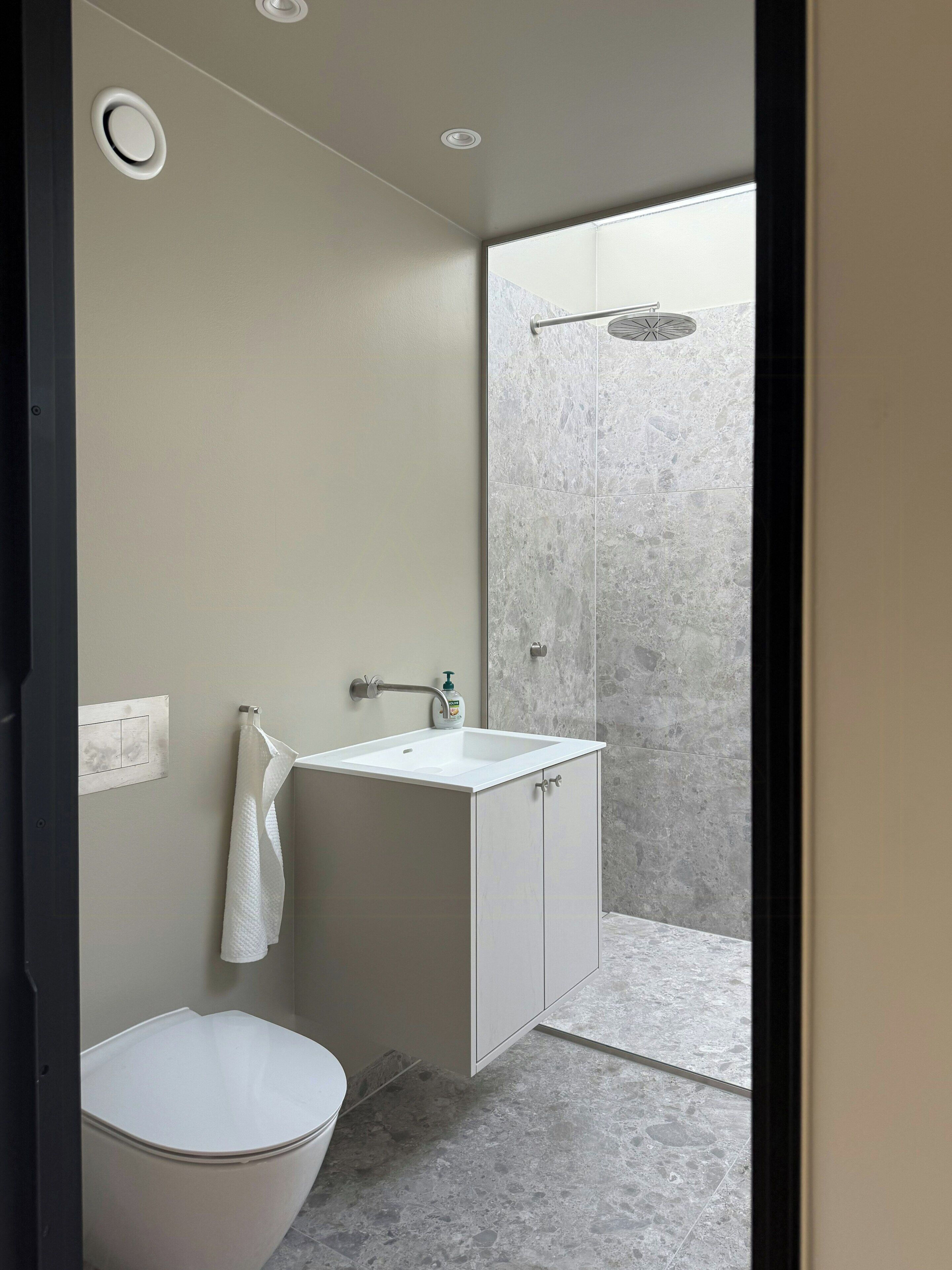 Un baño moderno con inodoro, lavamanos y ducha.