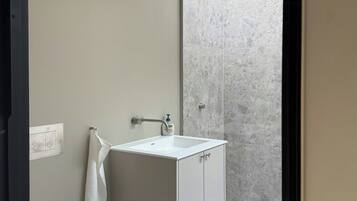 Un baño moderno con inodoro, lavamanos y ducha.