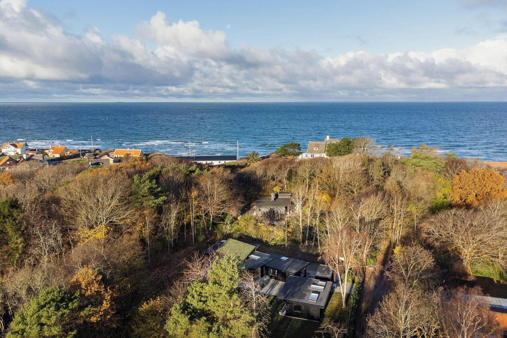 Une propriété située sur la côte, avec vue sur la mer, entourée d’arbres et de quelques bâtiments.