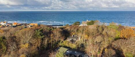 Une propriété située sur la côte, avec vue sur la mer, entourée d’arbres et de quelques bâtiments.