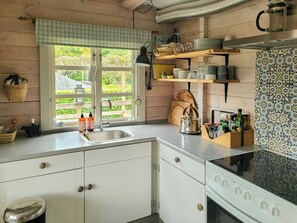 A kitchen with a window, a sink, a kettle, and a stove.