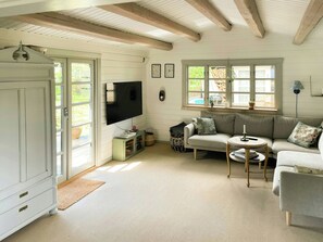 A living room with a sofa, a television, a cabinet, and a window with a view of the outdoors.