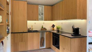 Una cocina moderna con armarios de madera, una encimera negra y un horno empotrado.