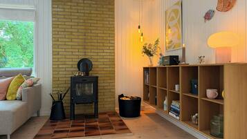 Una sala de estar acogedora con pared de ladrillo, un sofá con cojines, una estantería de madera y una chimenea.