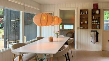 A dining area with a long table, chairs, and hanging lamps.